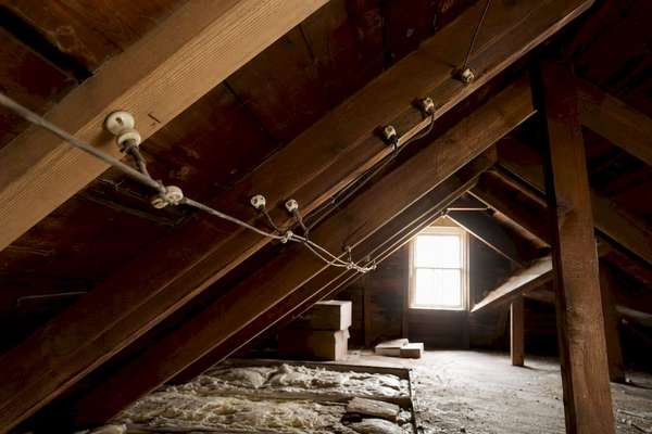 Close-up of original knob-and-tube wiring with ceramic knobs and bare conductors in an attic